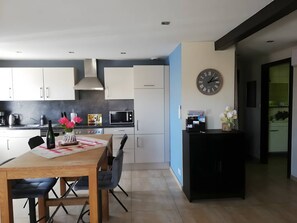 A modern kitchen with white cabinets, a black countertop, and a dining area with a wooden table and chairs.