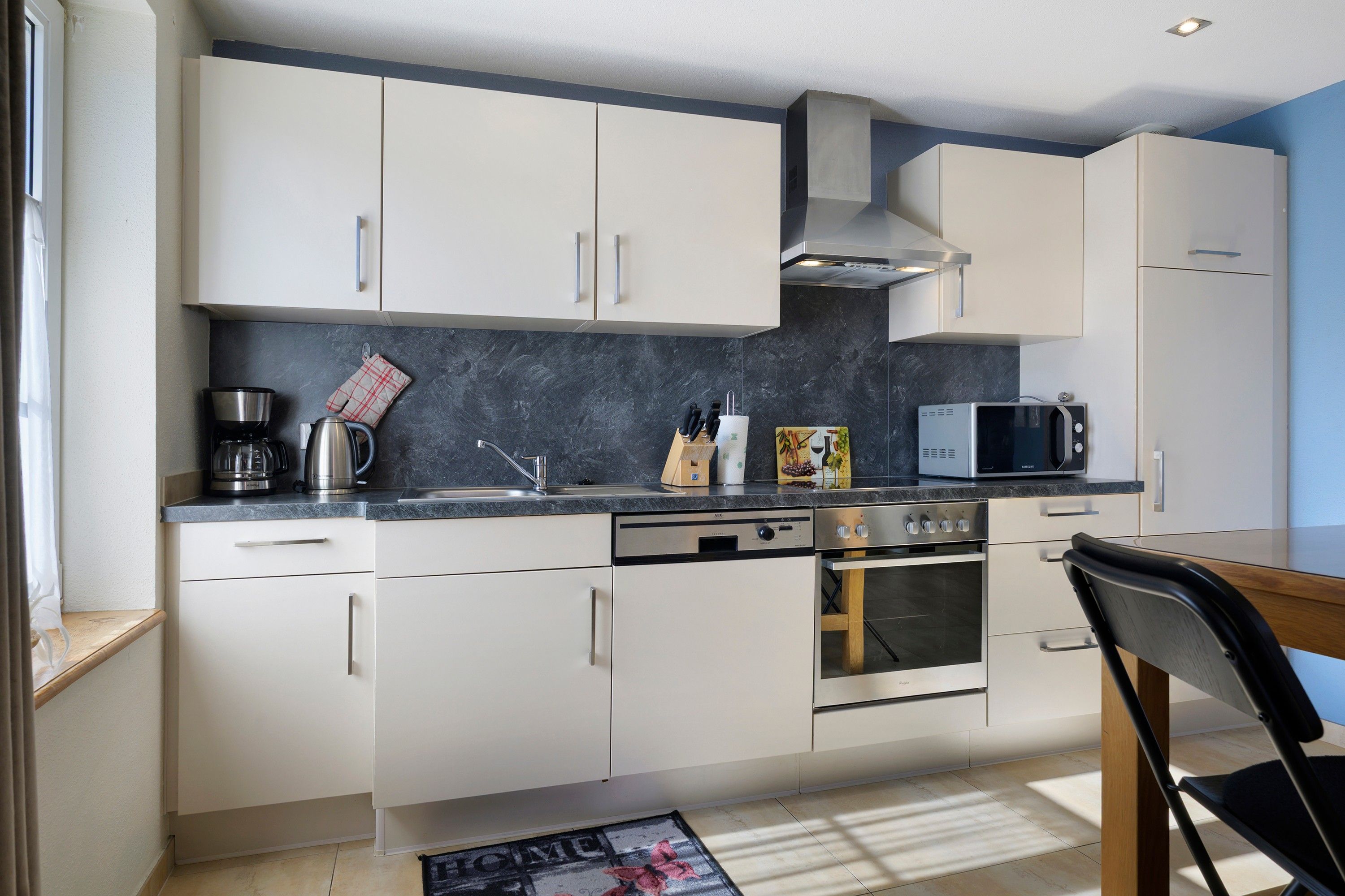 Una cucina moderna con mobili bianchi, piano cottura in acciaio inossidabile e forno a microonde.