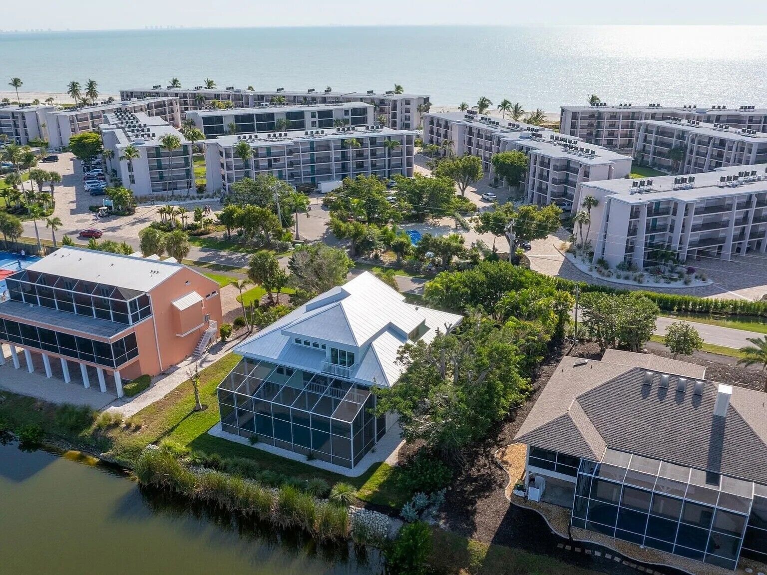 A coastal hotel complex with multiple buildings, a beach, and a body of water.