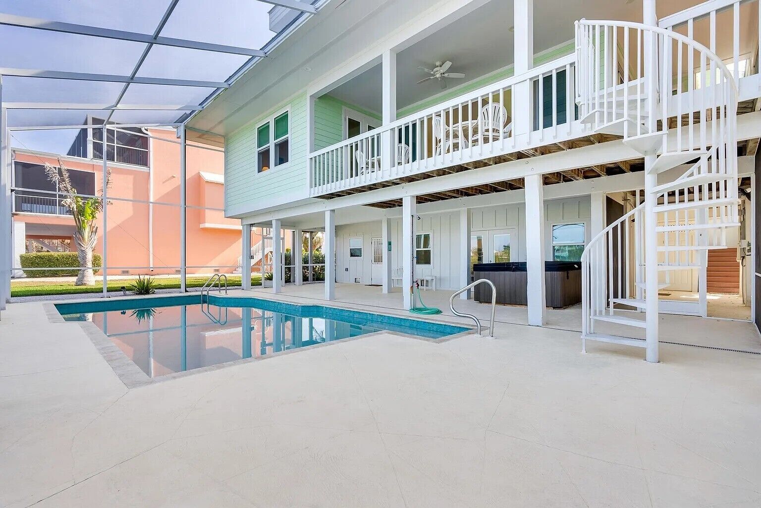 Un espace piscine extérieur à plusieurs niveaux, doté d’un escalier et d’un jacuzzi.
