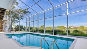 Una piscina con un rivestimento in vetro, circondata da un solarium bianco e una scala in metallo.