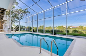 A swimming pool with a glass enclosure, surrounded by a white deck and a metal staircase. - Sanibel coastal charm, pool, across street from beach and Sundial-new on market (Sanibel)
