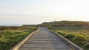 Une promenade en bois mène à une zone herbeuse d’où l’on peut admirer la mer.