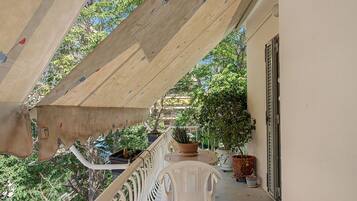 Ein Balkon mit Holzboden, Blumentöpfen und einem weißen Kunststoffstuhl.