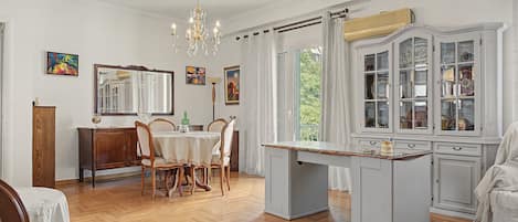 A dining area with a chandelier, wooden chairs, a table, and a cabinet with glass doors.