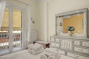 Ein Hotelzimmer mit Bett, Schminktisch, Spiegel und Blick auf den Außenbalkon.