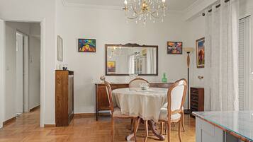 Zona pranzo con un tavolo rotondo, sedie, un lampadario e opere d'arte alle pareti.