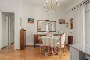 Ein Essbereich mit einem runden Tisch, Stühlen, einer Deckenleuchte und Kunstwerken an den Wänden.