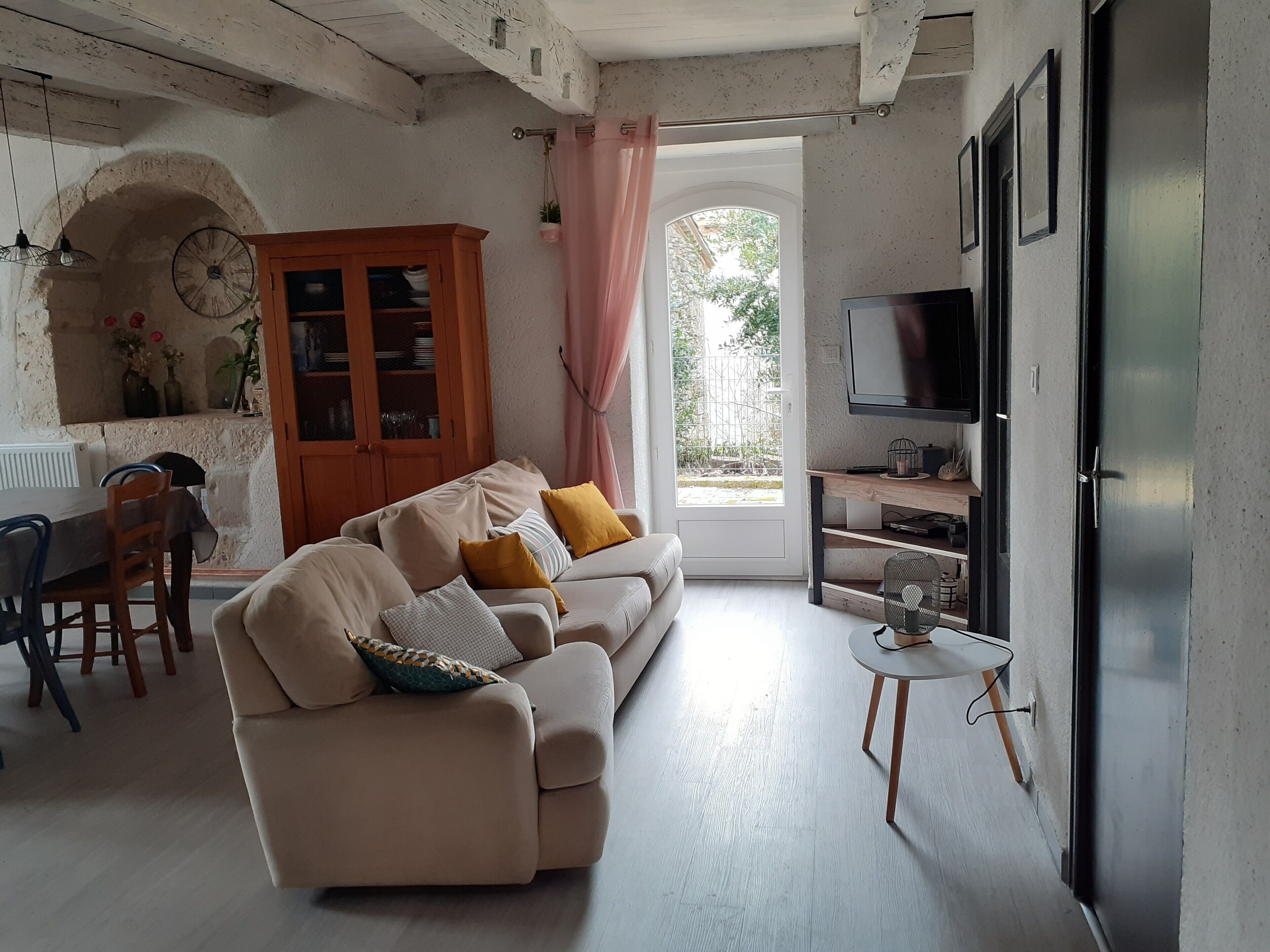 A living room with a sofa, a dining table, a cabinet, and a TV.