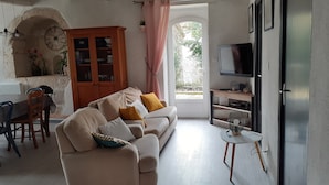 A living room with a sofa, a dining table, a cabinet, and a TV.