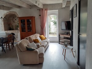A living room with a sofa, a dining table, a cabinet, and a TV.