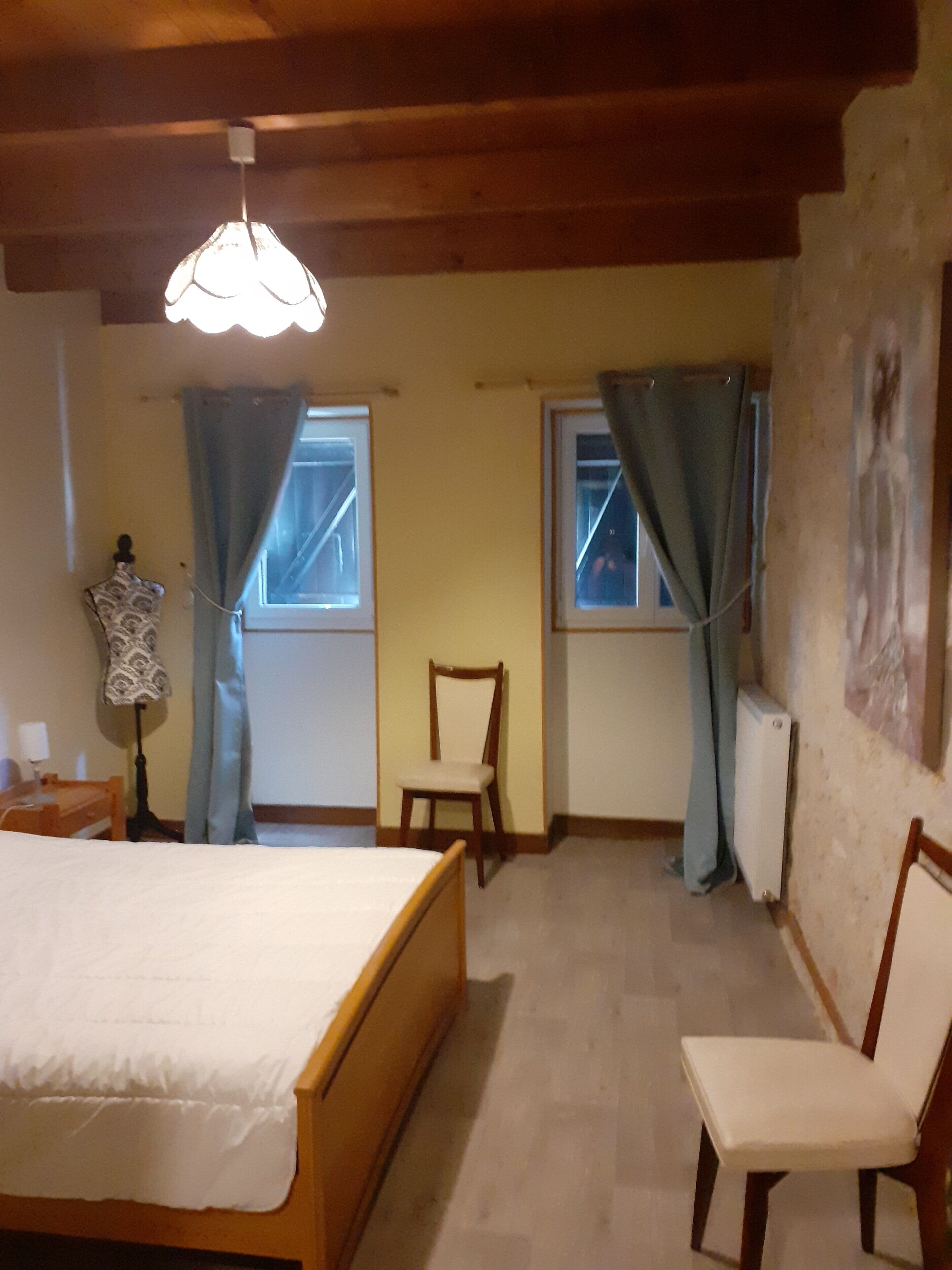 Una camera da letto con un letto, una sedia, un manichino e una finestra.