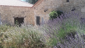 A stone building with a tiled roof, a door, and a window.