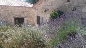 A stone building with a tiled roof, a door, and a window.