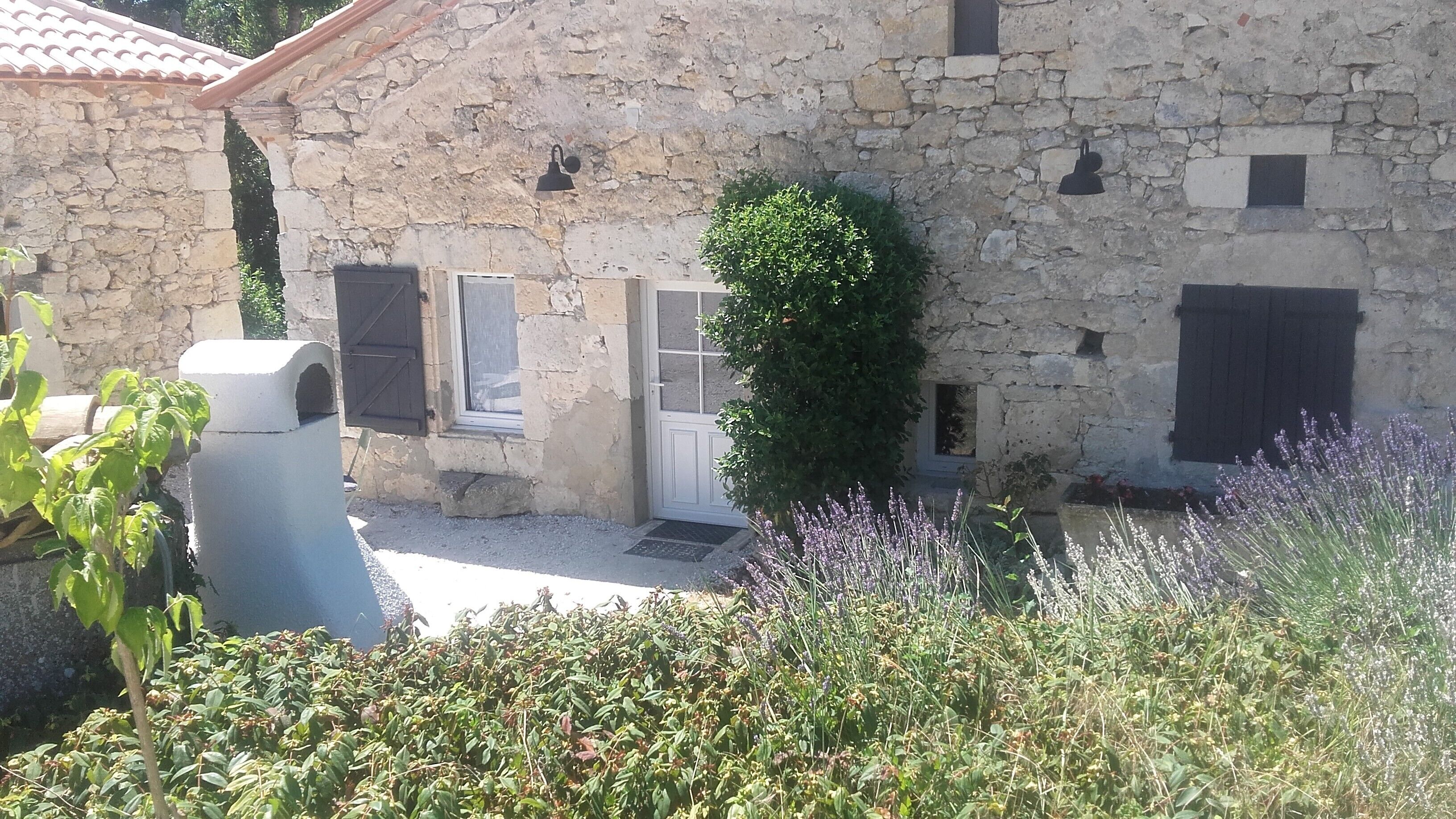 Un edificio de piedra con puerta, ventanas y un pequeño jardín de lavanda.