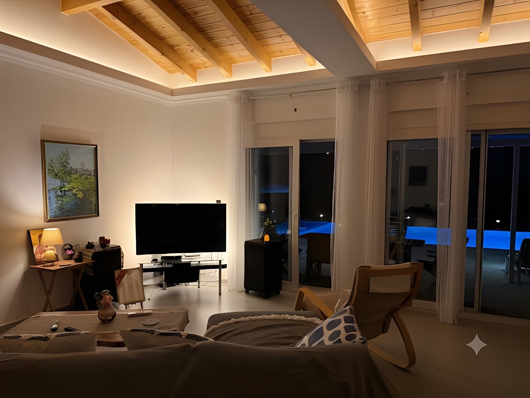 En moderne stue med et fladskærms-tv, et spiseområde med et blåt bord og store vinduer.