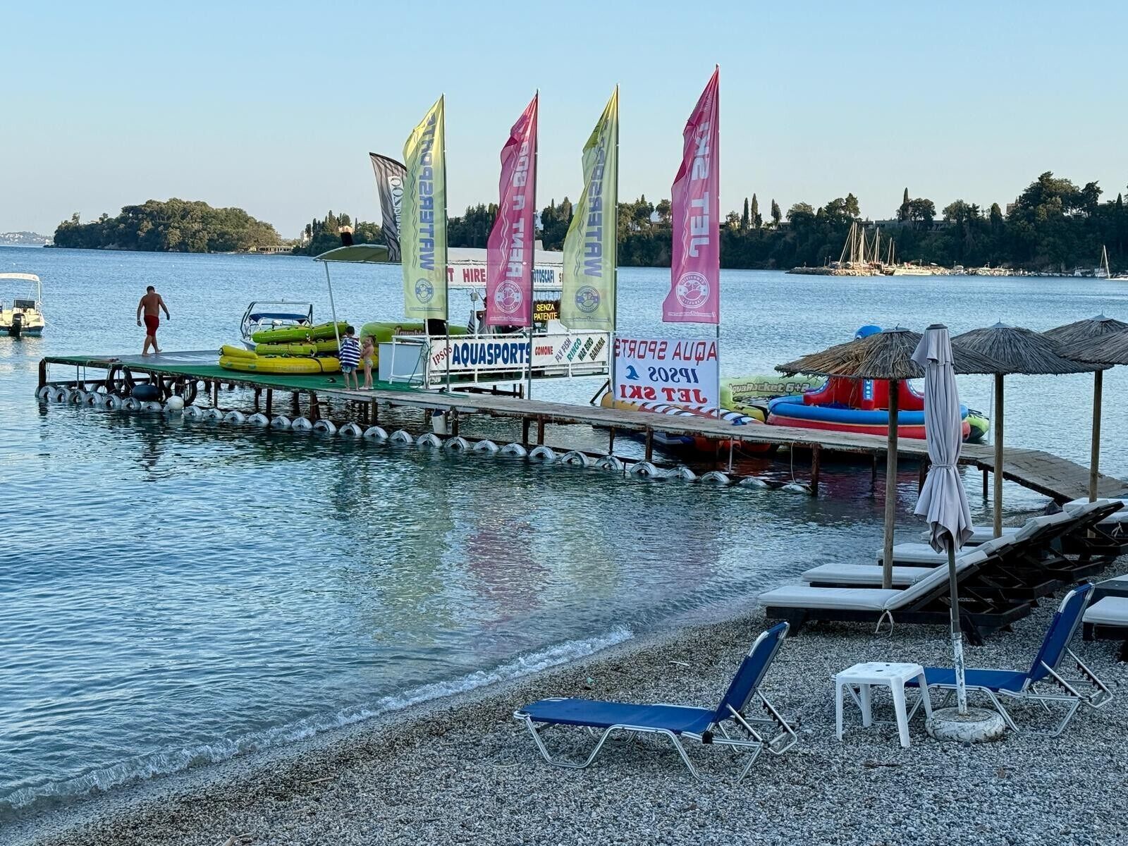 A waterfront area with a dock, inflatable boats, and beach chairs.