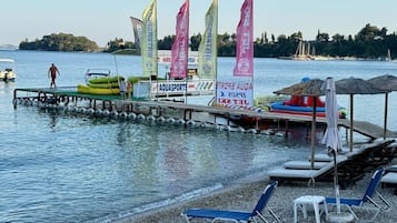 A waterfront area with a dock, inflatable boats, and beach chairs.
