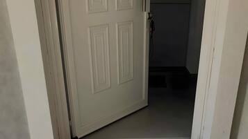 Een gedeeltelijk open deur die leidt naar een kamer, met een zichtbare deurklink en deuropening.