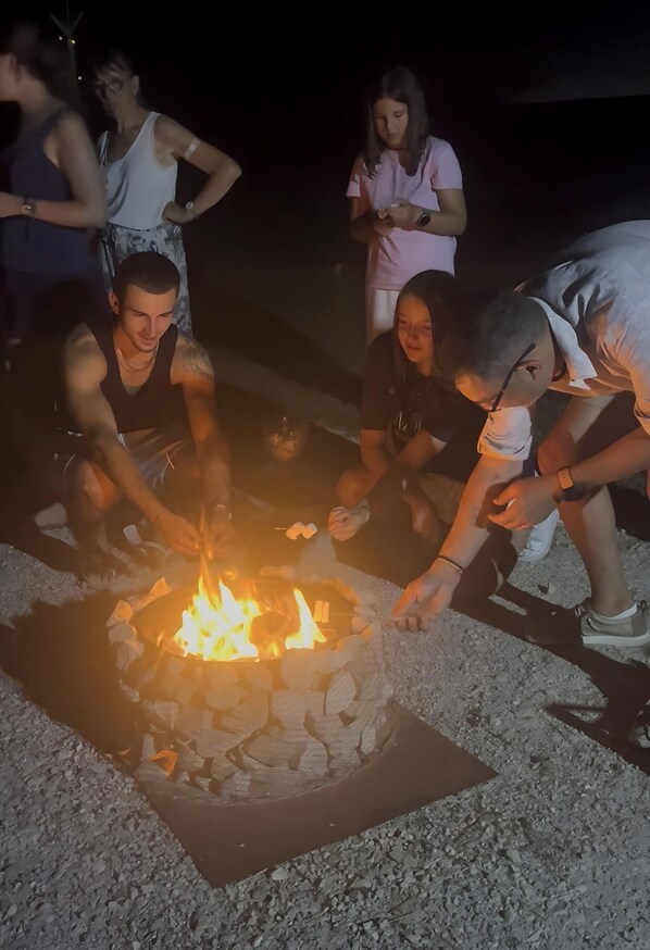 A group of people around a campfire with rocks forming a fire pit.