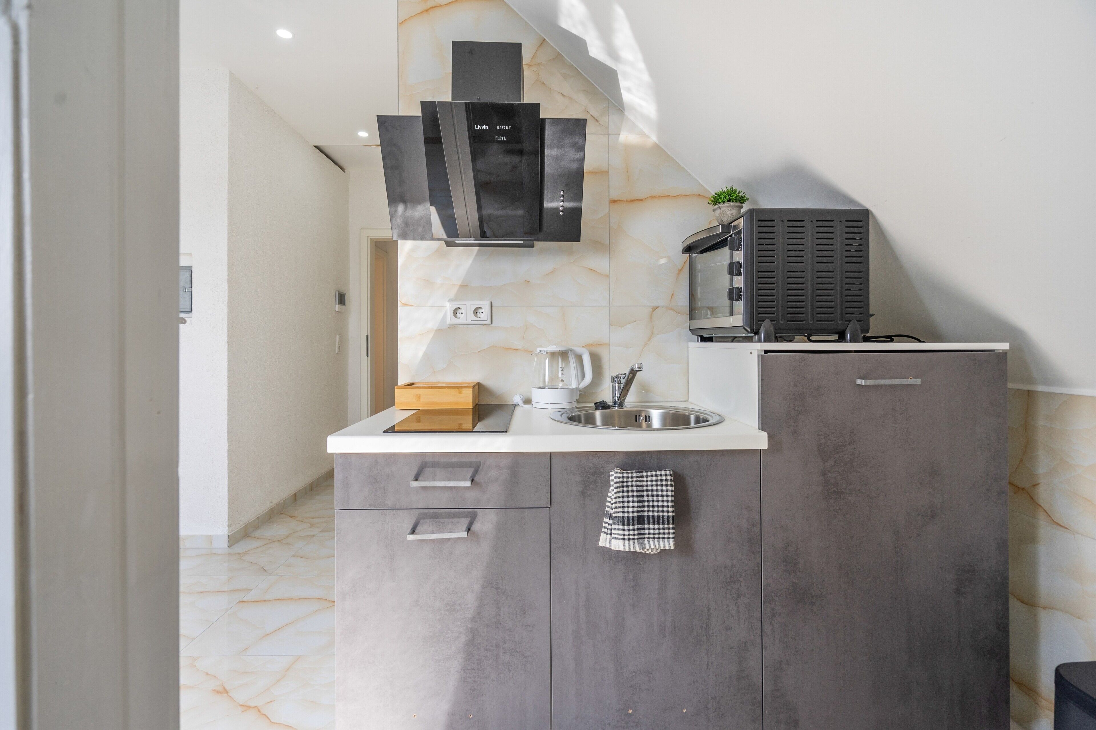 Eine moderne Küche mit Marmorfliesenspiegel, Backofen und Kaffeemaschine.