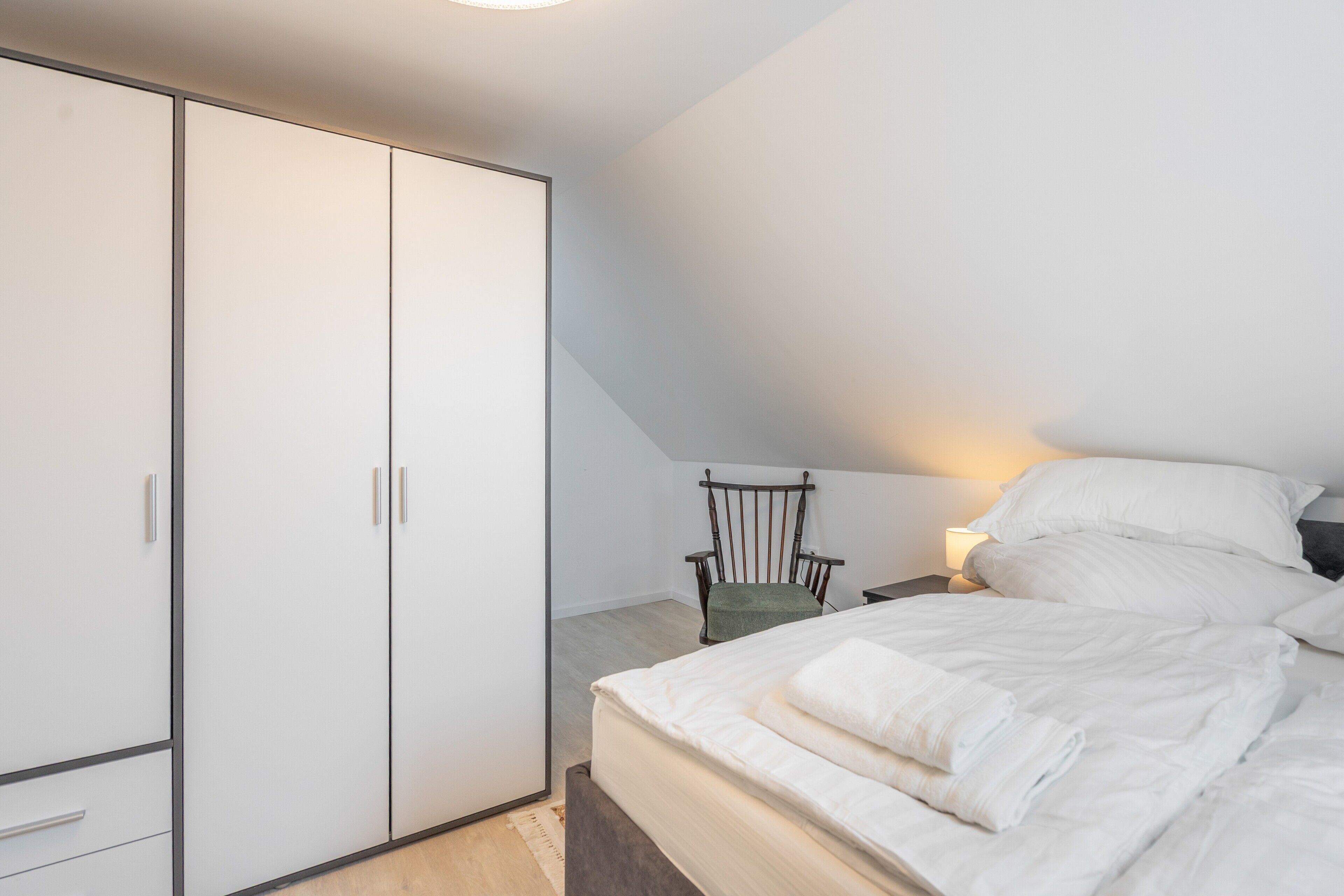 Ein Schlafzimmer mit Bett, Stuhl und Kleiderschrank.