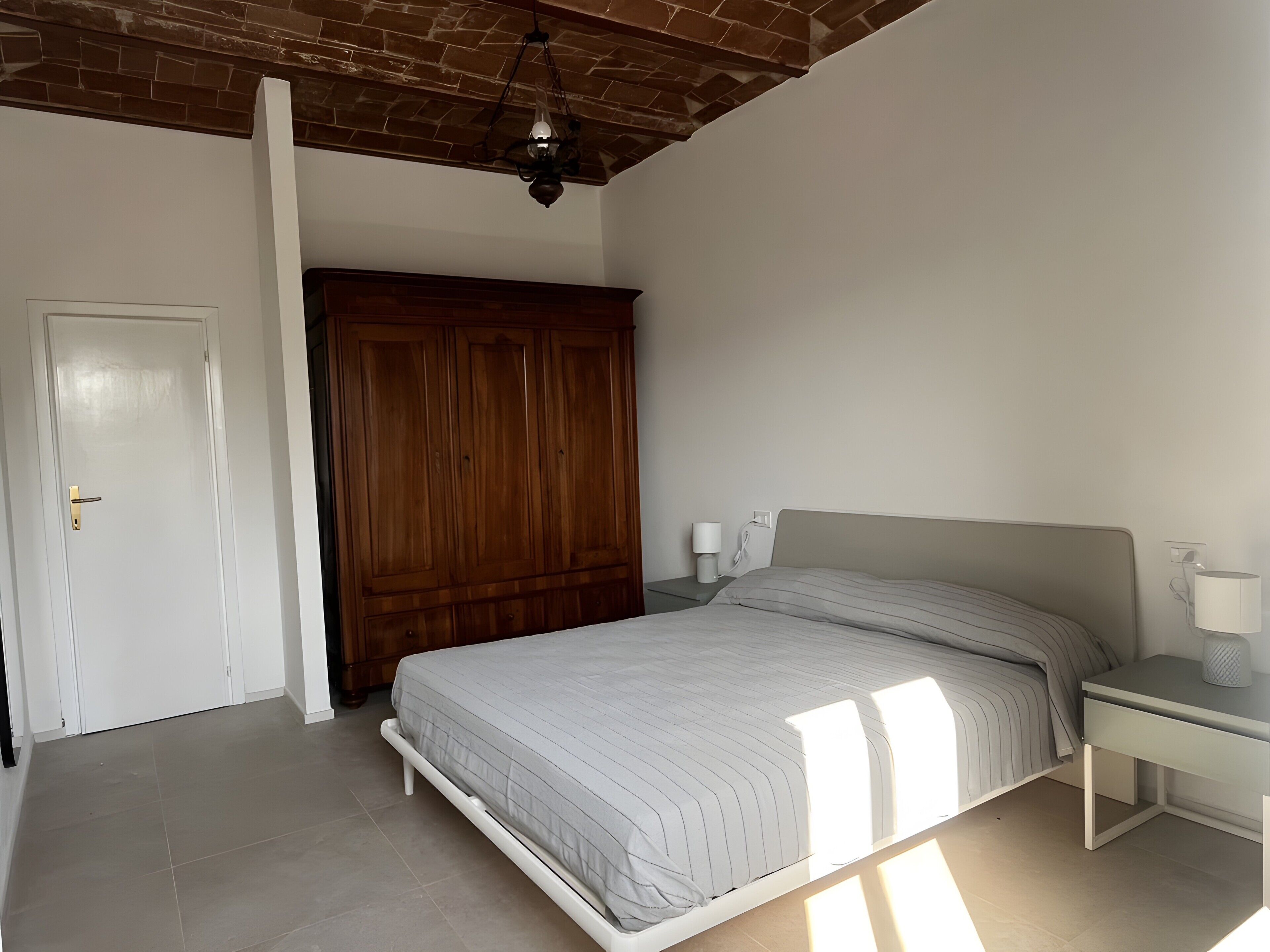 Un dormitorio con cama, mesita de noche, armario y ventilador de techo.