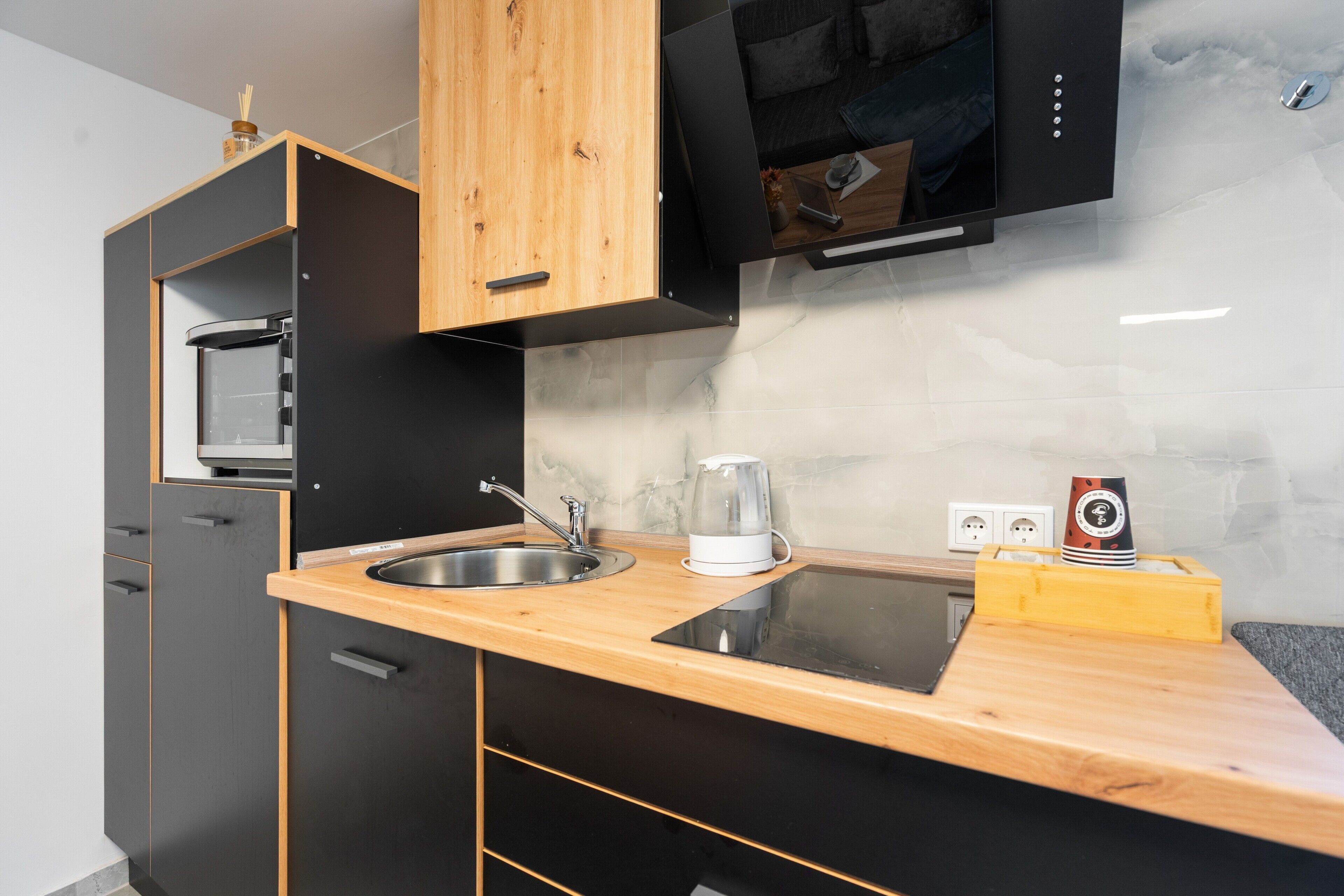 Una cocina moderna con encimera de madera, pileta de acero inoxidable y microondas integrado.