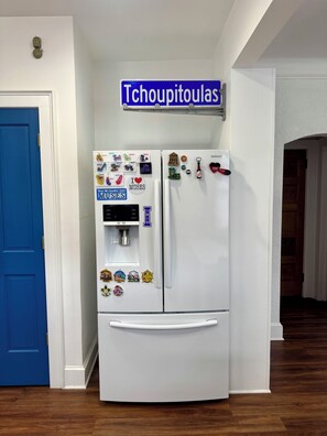 A white refrigerator with magnets and a blue sign above it. - Sweetest Spot in the Big Easy! Colorful 2/2 in fantastic walkable neighborhood! (New Orleans)
