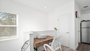 Een kleine keuken met witte kasten, een houten aanrechtblad en een inbouwkoelkast.
