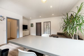 Eine moderne Küche mit einer großen Kochinsel, eine Essecke mit einer Couch und ein Wohnzimmer mit Fernseher und Kunstwerken.