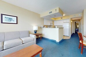 A hotel room with a sofa, a small table, a kitchenette, and a dining area. - Carolinian Beach Resort 1831 (Myrtle Beach)