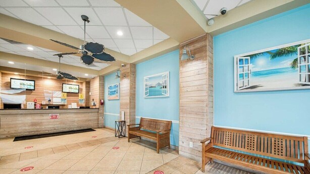 Una zona de recepción con mostrador de madera, ventilador de techo y banco.
