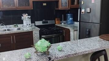 A kitchen with granite countertops, a stove, a refrigerator, and wooden cabinets.