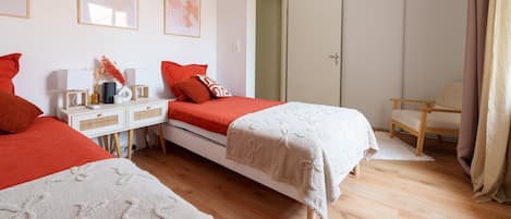 Une chambre avec deux lits, une table de chevet, une chaise, une armoire et un luminaire suspendu.