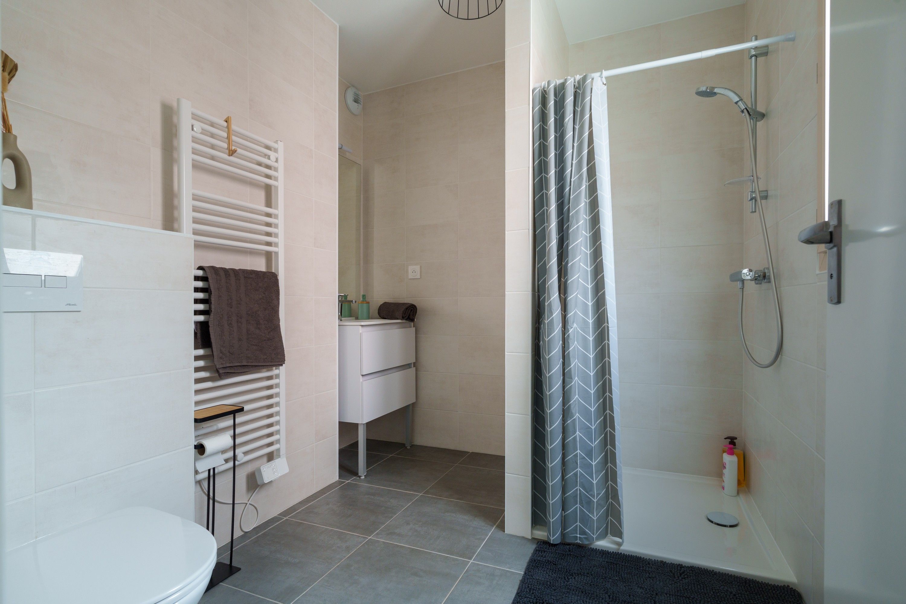 Une salle de bain moderne équipée d’une douche, de toilettes et d’un porte-serviettes.