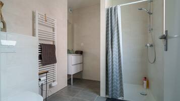 Une salle de bain moderne équipée d’une douche, de toilettes et d’un porte-serviettes.