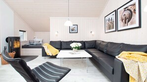 A modern living room with a sectional sofa, a small table, a fireplace, and two framed pictures on the wall. - Grobenbrode Mehrgenerationen-strandrefugium (Grossenbrode)