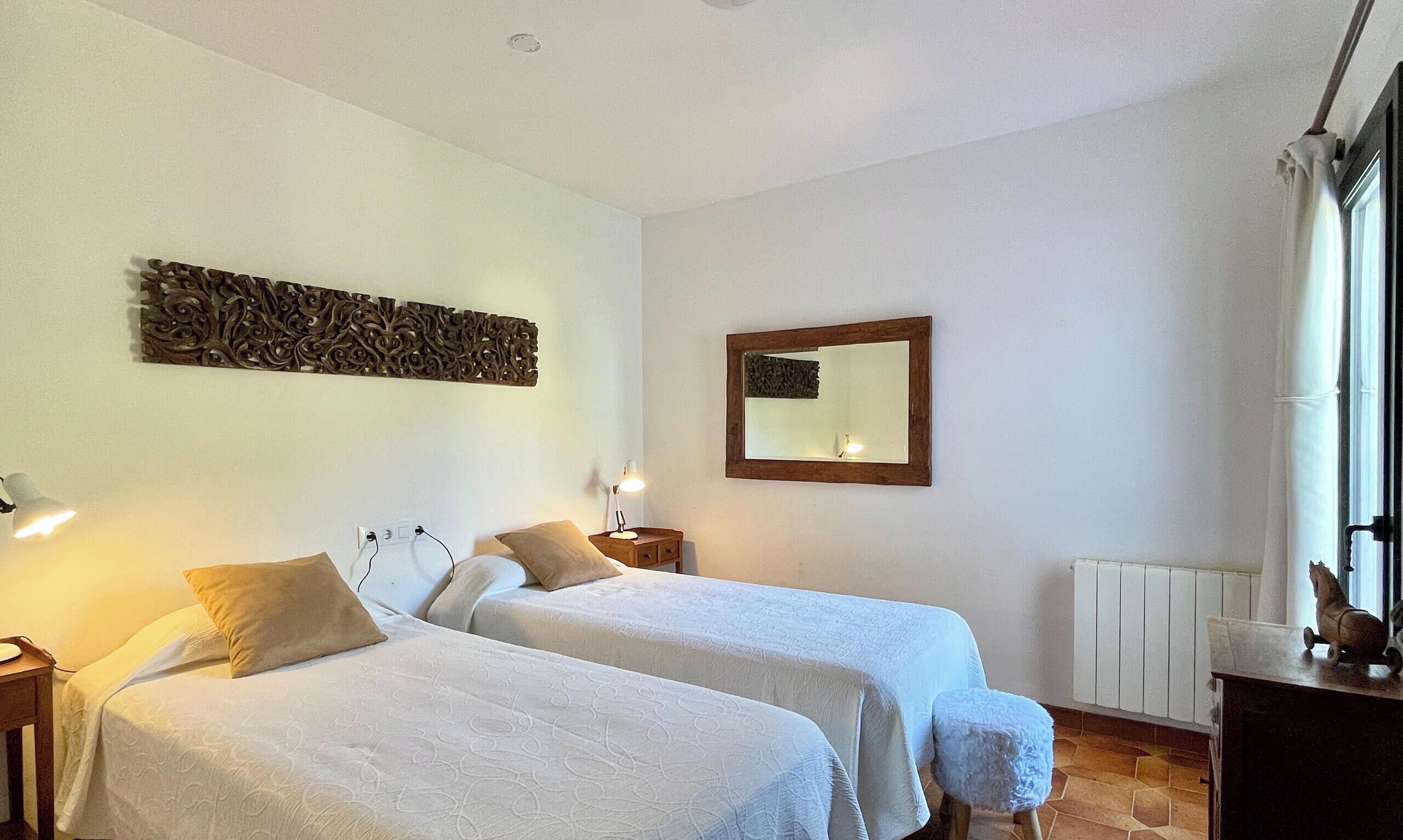 Habitación de hotel con dos camas, un adorno en la pared, un espejo y un radiador.