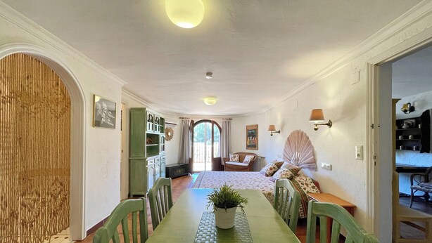 A dining area with a long table, chairs, and a potted plant. There is a sofa and a fan in the background. - Villa in Benissa with private pool for 8 guests | Costa Blanca holiday rental - ALELUYA (Benissa)
