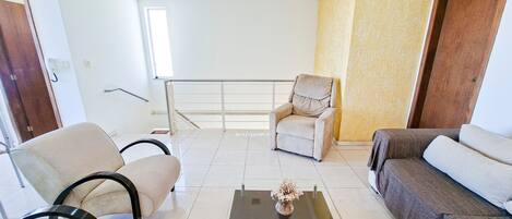 Una sala de estar moderna con un sofá, sillones, una mesa de centro y una butaca.