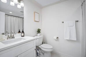 A modern bathroom with a white sink, a toilet, and a shower curtain. - Newly Built: C: 1BR/1BA/Modern Condo in Houston (Houston)