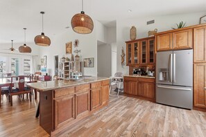 Eine geräumige Küche mit Holzschränken, einem Edelstahlkühlschrank und einem Essbereich mit großem Tisch und Stühlen.