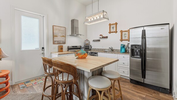 Una cucina moderna con isola centrale, elettrodomestici in acciaio inossidabile e un lampadario a sospensione.