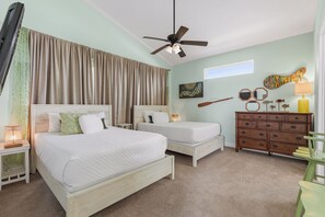 Ein Schlafzimmer mit zwei Betten, einem Deckenventilator, einer Kommode und Bildern an der Wand.