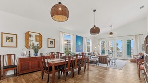 Un'ampia sala da pranzo con un tavolo e sedie in legno, una grande finestra con vista e una ventola a soffitto.