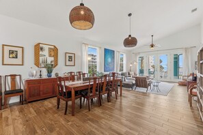 Ein geräumiger Essbereich mit Holztisch und Stühlen, einem großen Fenster mit Aussicht und einem Deckenventilator.