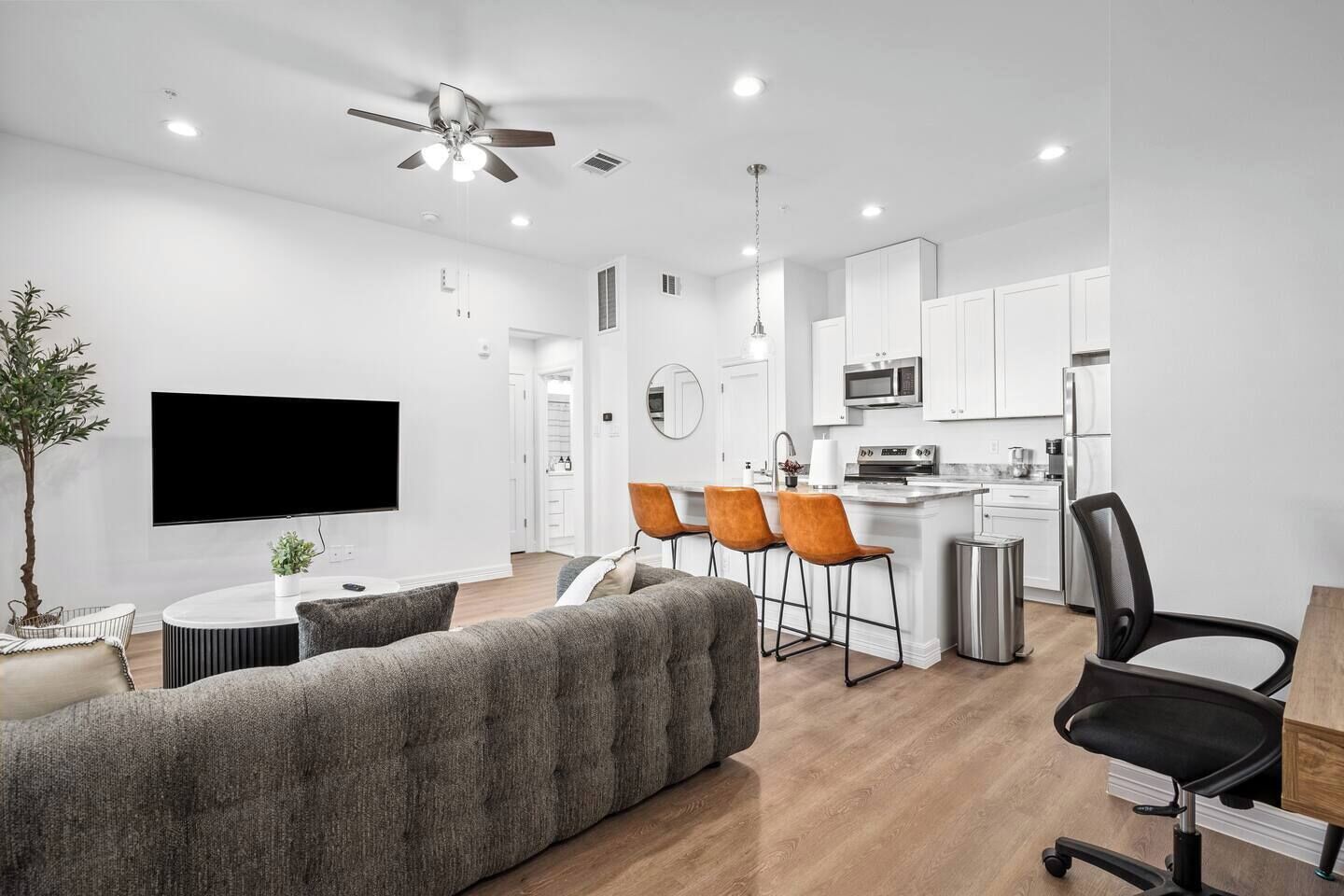 A modern living room with a flat-screen TV, a sofa, and a dining area with chairs.