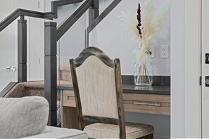 A modern kitchen with a wooden chair, a vase with dried plants, and a staircase. - 
Stylish 4BR 5Bed Oasis | Fast Wi-Fi & Free Parking (Edmonton)