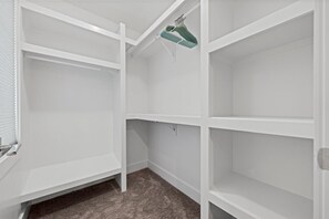 Ein weißer Kleiderschrank mit Regalen und Kleiderstangen.